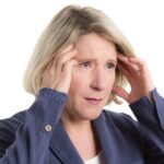 Woman touching her temples, looking distressed.