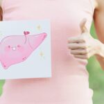 Woman holding a happy liver illustration with thumbs-up gesture.