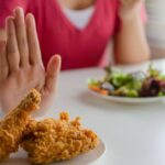 Person rejecting fried chicken, opting for a plate of salad.