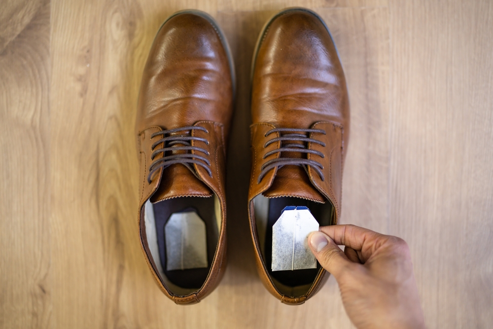 a person placing a sachet of moisture-absorbing material inside a brown leather shoe.